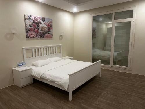 a bedroom with a bed and a painting of roses at Shaleeh 285 شاليه العائلة in Al Khīrān