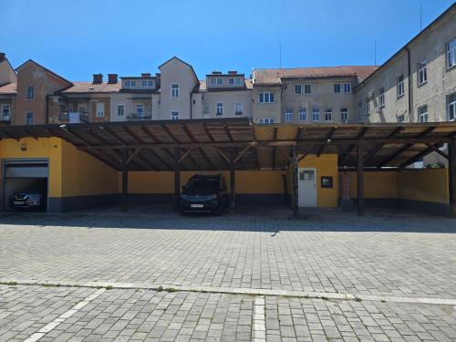 a parking lot with a car parked under a wooden structure at Apartments Fazarinc with parking, wellness and city store in the center of Celje in Celje
