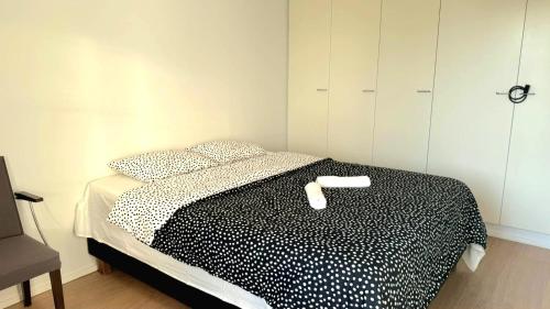 a bedroom with a black and white bed with a chair at Delux room with Sauna in Espoo