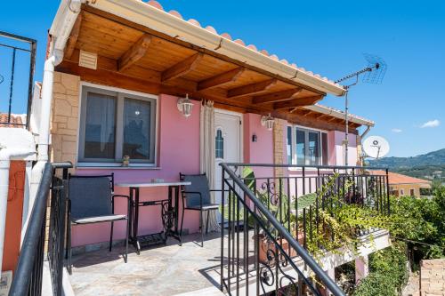 a pink house with a table and chairs on a balcony at Violas Studio in Ágios Matthaíos