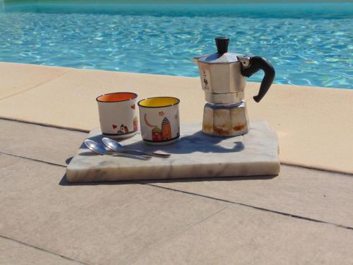 a tea pot and three cups on a towel next to a pool at Appartamenti Ca'Melia in Sarzana