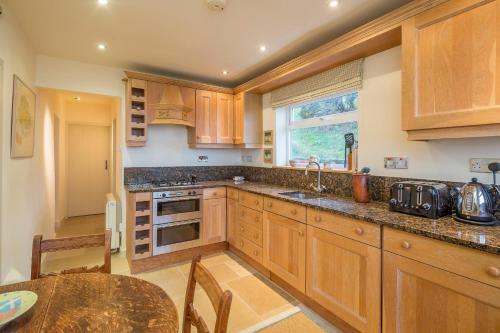 a kitchen with wooden cabinets and a table and a window at Rhiw 2 Bryn Tirion in Rhiw