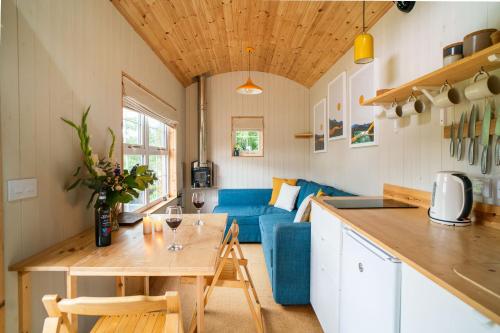 a kitchen and living room with a blue couch at Ailsa- Enchanting Tiny House with wood burner and hot tub in Cairngorms in Ballater