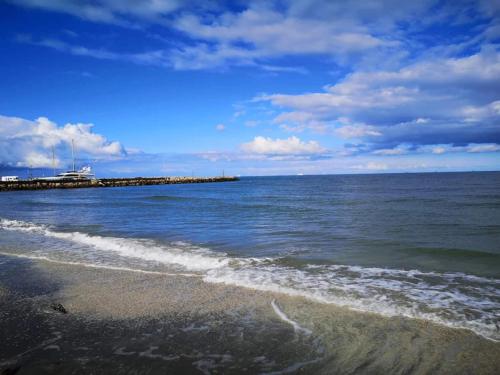 a beach with the ocean and a pier in the background at 10 person holiday home in Ålbæk in Ålbæk