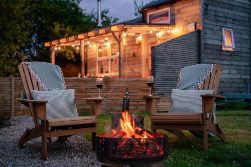 two chairs and a fire pit in front of a cabin at Ailsa- Enchanting Tiny House with wood burner and hot tub in Cairngorms in Ballater