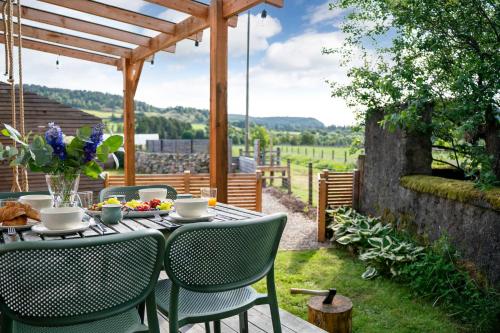 a table and chairs on a patio with a view at Ailsa- Enchanting Tiny House with wood burner and hot tub in Cairngorms in Ballater