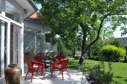 um pátio com cadeiras vermelhas, uma mesa e uma árvore em Kertes em Veszprém