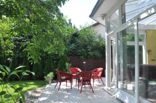 een patio met rode stoelen en een tafel in de tuin bij Kertes in Veszprém