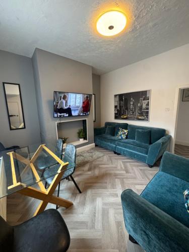 a living room with blue couches and a tv at 4 Bedroom House, Central City Location in Newcastle upon Tyne
