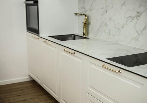 a white kitchen with a sink and a microwave at Modern Apartment Peje in Peje
