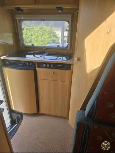 a kitchen with a stove and a window in an rv at Bobil hotell Caravan in Sandefjord