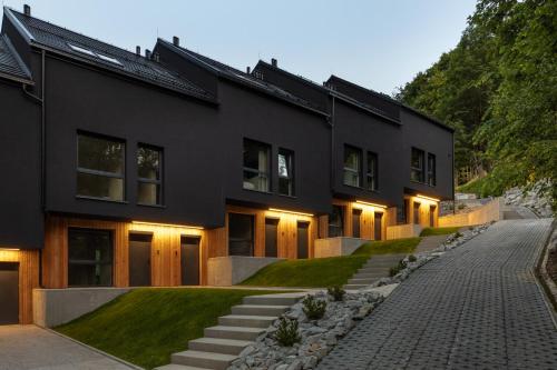 a black house with a cobblestone driveway at WIDOQ Resort Szczyrk in Szczyrk