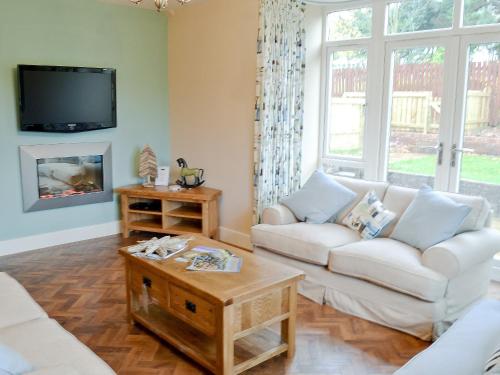 ein Wohnzimmer mit einem weißen Sofa und einem Fernseher in der Unterkunft Salar's Rest - 28028 in Alnmouth