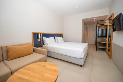 a hotel room with a bed and a couch at Smy Kos Beach & Splash in Mastichari