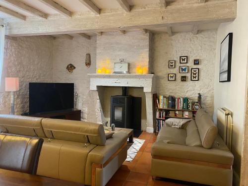 a living room with a couch and a fireplace at Le relais de l'ancienne poste in Sigoulès