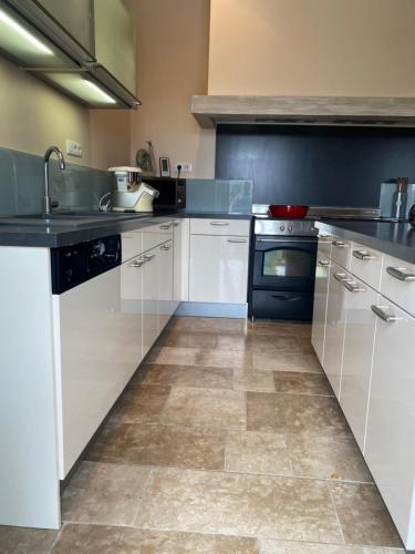 a kitchen with white cabinets and black appliances at Le relais de l'ancienne poste in Sigoulès