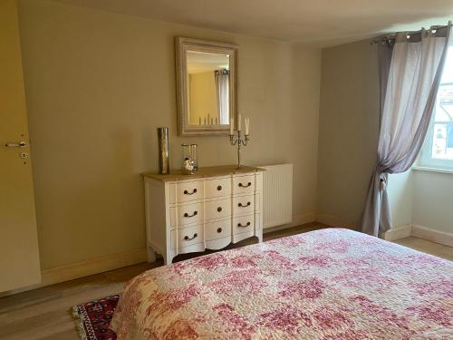 a bedroom with a bed and a dresser with a mirror at Le relais de l'ancienne poste in Sigoulès