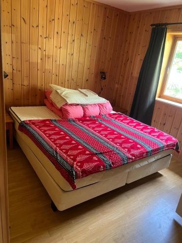 a bed with a red comforter in a room at Hytte Elvdal in Nymoen