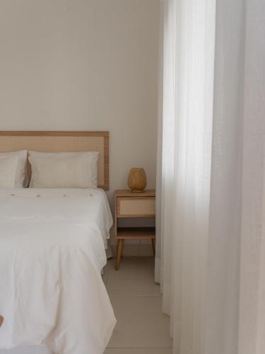 a white bedroom with two beds and a night stand at Olisa Praia Hotel in Maresias