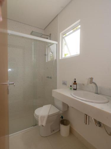 a bathroom with a toilet and a sink and a shower at Olisa Praia Hotel in Maresias