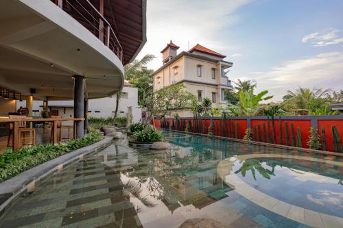 a swimming pool in front of a house with a building at Artropeace Ubud Retreat & Villas in Ubud