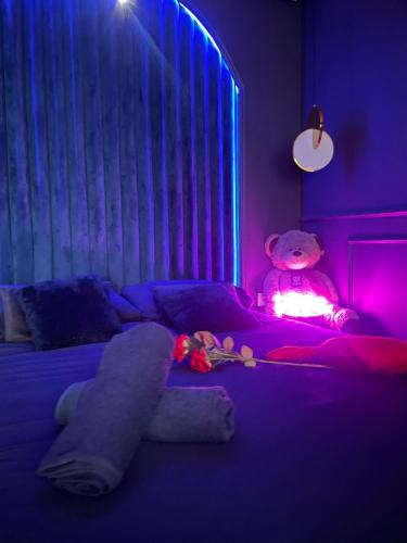 a teddy bear sitting on a bed in a purple room at Love Room 85 in Kortrijk