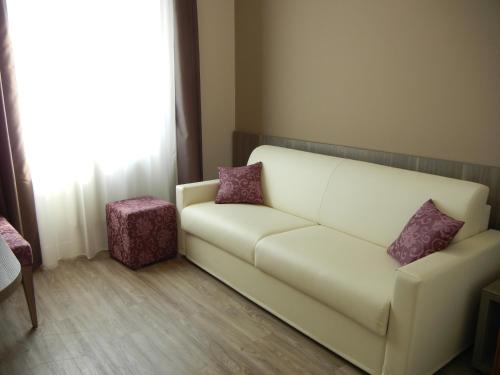 a living room with a white couch with purple pillows at Delle Nazioni Milan Hotel in Milan