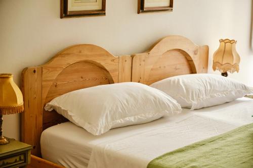 a bedroom with a wooden bed with two white pillows at Villa Montalban Ghetti - La Fiorita in Conegliano