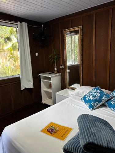 a bedroom with a bed with blue pillows and a window at RECANTO DO SOL "Aluguel de quartos - Hospedagem Simples" in Ilha do Mel