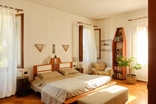 a bedroom with a large bed and a chair at Villa Montalban Ghetti - La Fiorita in Conegliano