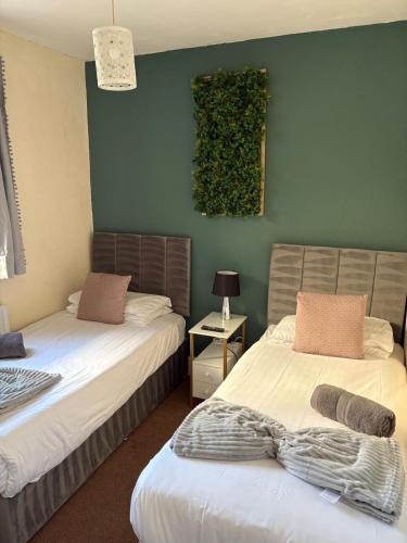 a bedroom with two beds and a green wall at Bronte House - Blackpool in Blackpool