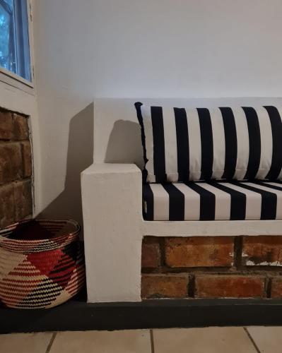 a black and white couch sitting next to a brick wall at Tofo Beach Gardens in Inhambane