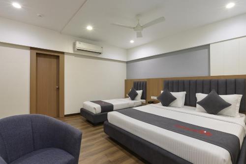 a hotel room with two beds and a chair at The Sky Imperial Welcome, Somnath in Somnath