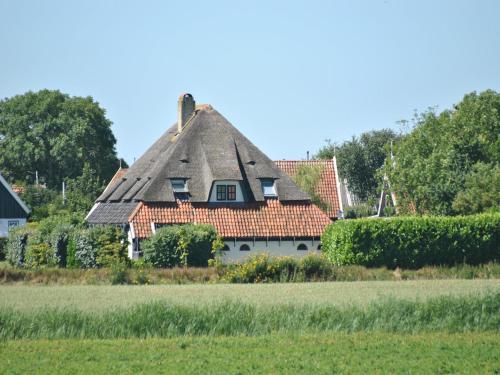 a house with a thatched roof in a field at Farmhouse Lodge in Texel near the Dyke in Oost
