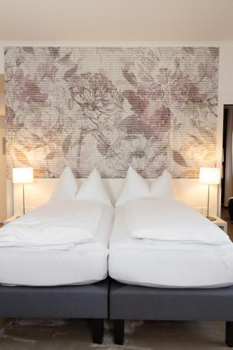 a bed with white pillows and a floral wall mural at Hotel Vitznauerhof - Lifestyle Hideaway at Lake Lucerne in Vitznau