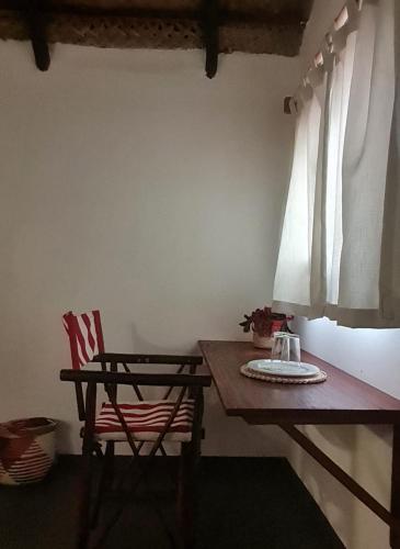 a table and a chair in a room with a table and a window at Tofo Beach Gardens in Inhambane