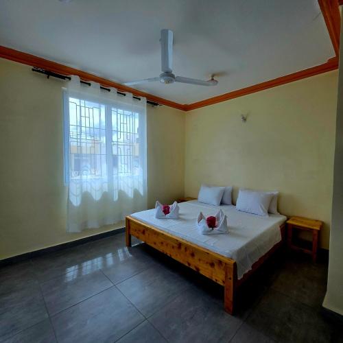 a bedroom with a bed with white sheets and a window at SAFARI BREEZE Residence in Gatunga