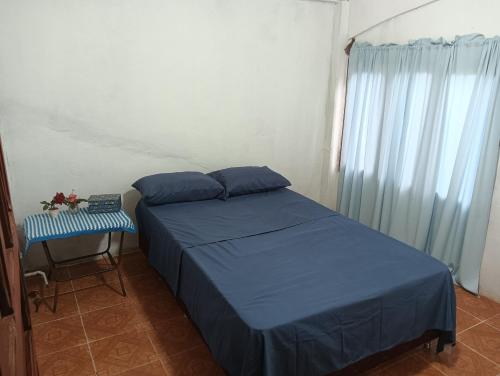a bedroom with a bed with blue sheets and a table at Familia Cabrera Rojas in Nueva Alborada