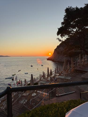 a beach with chairs and umbrellas at sunset at Isolotto Guest House in Porto Ercole