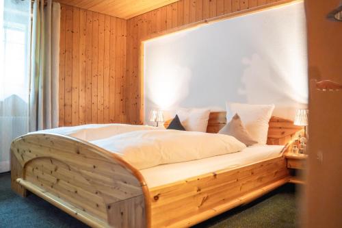 a bed in a room with a wooden wall at Hotel Gasthaus Schäfle in Bürserberg