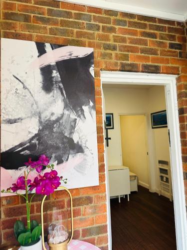 a brick wall with a painting and flowers in a vase at House in Nedlands, Venice in Perth
