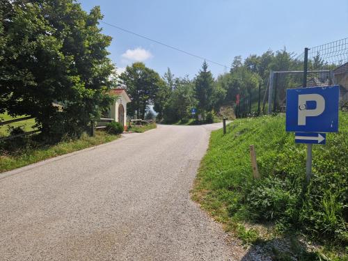 an empty road with a blue parking sign on the side at AirWood Glamping in Križe