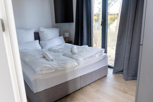 un letto con lenzuola bianche sopra in una stanza di Mobile Homes Holland - Jersleber See Camping & Erlebnisresort a Jersleben