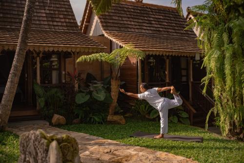 a woman doing yoga in front of a house at Artropeace Ubud Retreat & Villas in Ubud