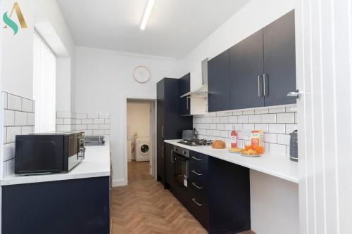 a kitchen with black cabinets and a microwave at Thornaby Road TSAC in Stockton-on-Tees