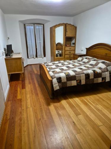 a bedroom with a bed and a wooden floor at L'Appartamento d'Elda in Santa Maria Maggiore