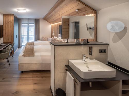 a bathroom with a sink and a bed in a room at Mäsers Allgäuherz in Wiggensbach