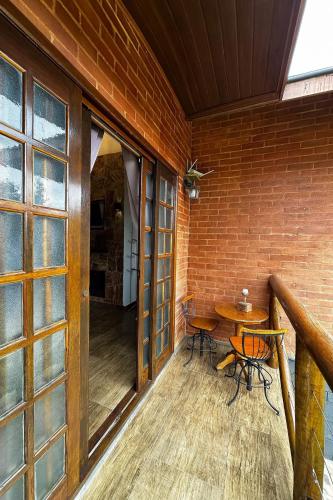a balcony with a table and chairs on a brick wall at Pousada Chales da Mantiqueira - Campos do Jordão in Campos do Jordão
