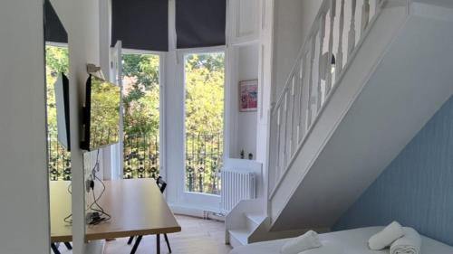 a room with a bed and a desk and a staircase at Charmstay Swiss Cottage in London