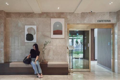 a woman sitting on a bench in a lobby at Hotel Yaja Mokpo Peace Square in Mokpo